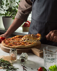 Men hold a pieсe of homemade pizza with food ingredients: cheese, pepperoni or salami, chicken pieces and mushrooms. Homemade food concept.