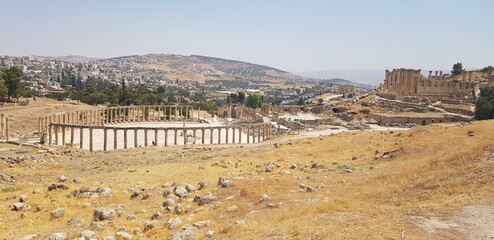 Le célèbre site touristique jordanien - Jerash, avec ses constructions ou grandes portes à moitié démolies ou partielles, grande zone de vestige historique et de style romain, plaine d'herbes secs
