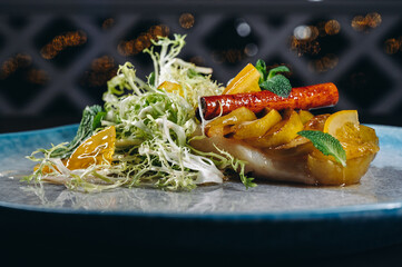 halibut fillet with fruit garnish on a blue ceramic plate