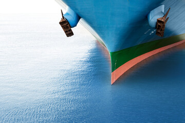 Front view of large blue merchant cargo ship in the middle of the ocean. Performing cargo export...