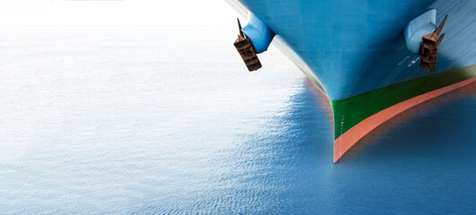 Front view of large blue merchant cargo ship in the middle of the ocean. Performing cargo export...