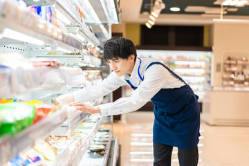 食品スーパーで品出しをする若いスタッフ