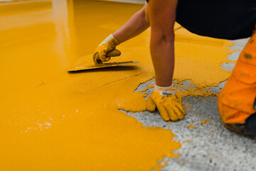 Professional construction worker applying floor paint or a new layer for a epoxy cast coating floor