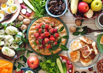 Fototapeta na wymiar Fragment of a table with vegetarian simple healthy food, cake with strawberries, breadcrumbs, potatoes, egg, herbs. Festive rustic table.