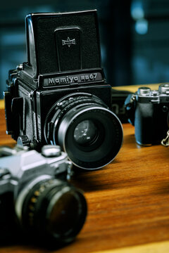 Illustrative editorial Close up shot of Mamiya RB67 medium format analog film camera and other cameras defocused on the background.