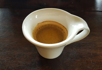 A cup of red coffee on a wooden table ready to drink