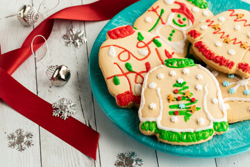 A plate of ugly Christmas sweater cookies with decorations to the left.