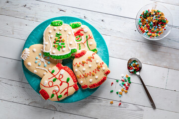 A plate of ugly Christmas sweater cookies with a bowl of sprinkles to the side.
