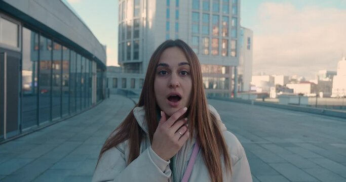 Oh my god wow concept. Amazed excited young caucasian business woman successful girl raising hands in surprise looking at camera with shocked face happy with victory standing in urban city.