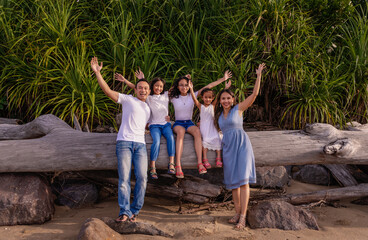 family, leisure and people concept-young active parents with three daughters with arms up- enjoying summer vacation together. Big asian happy family of five
