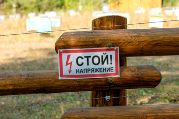 Warning on a wooden fence. Russian text: Stop. Voltage