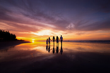Silhouettes of big happy family holding the hands on beach during sunset