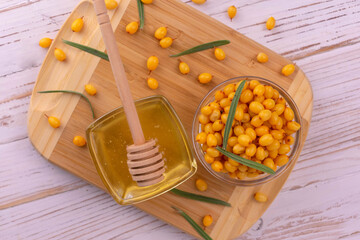 Sea buckthorn and honey on a wooden board. Flat lay.
