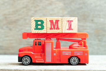 Fire ladder truck hold letter block in word BMI (abbreviation of body mass index) on wood background