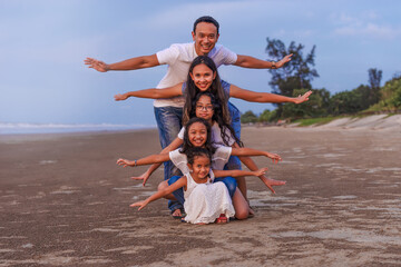 Happy Asian diversity generation family having fun together with open arms on tropical beach at summer. Smiling big family parents with children enjoy travel vacation