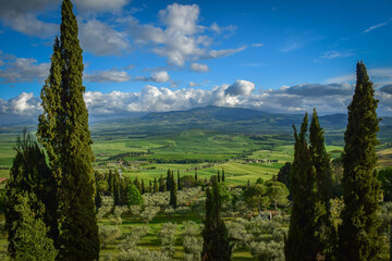 Tuscany, Italy 2019, view of a green valley with cypresses against a blue sky