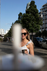 wunderschöne Frau in der City Berlin im Weißen Kleid und Sonnenbrille erlebt einen digitalen Tag voller Lifestyle