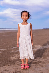 summer, childhood, leisure and people concept-full length of cute asian girl smiling on the beach in white dress