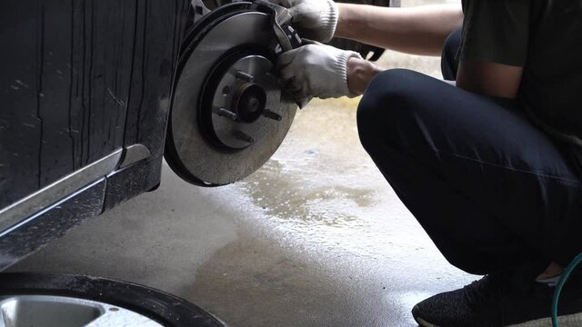 Mechanic is replacing new brake discs and new brake pads in the garage. Auto mechanic fixing car brakes in garage.