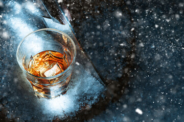 a glass of whiskey in the snow. concept of a warming drink on a cold winter evening.