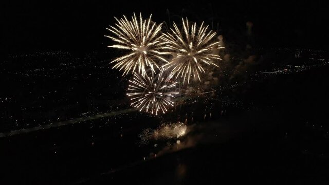 Drone video of red and green golden firework going up high to the sky over city at night. Firework show at the end of celebration. Golden firecracker at night. High quality 4k footage