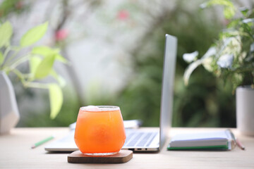Carrot juice and laptop on wooden desk