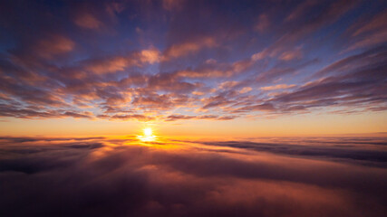 Fototapeta na wymiar Drone photo of setting sun above clouds in the sky. Dramatic drone photo flying high in the clouds