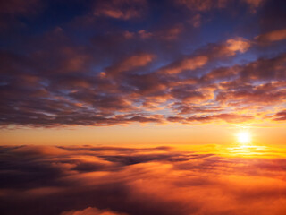 Beautiful landscape of setting sun from the sky. Dramatic sunset from the plane above bright clouds