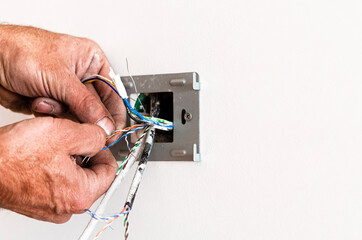 The hands of an elderly man mount a rosette in a white wall. Repair of the apartment