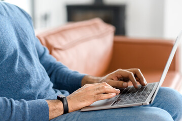 Close up image of male hands typing text on the laptop keyboard, working, responding to client...