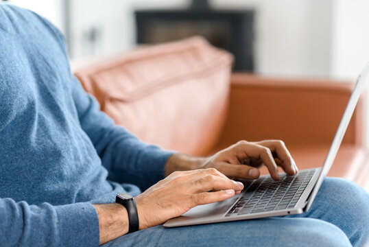 Close up image of male hands typing text on the laptop keyboard, working, responding to client e-mail, buying ordering items online. Electronics and modern wireless technology concept
