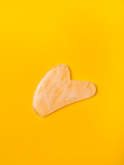 rose quartz scraper for traditional chinese face massage gua sha isolated on yellow background