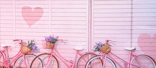Painted pink bicycles with baskets with flowers stands on the pebble on the background of the...