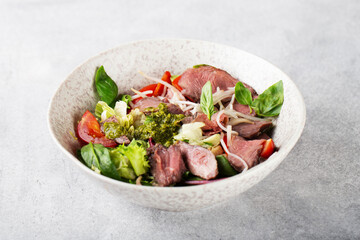 salad with roast beef and oyster mushrooms, herbs, cherry, basil and pesto sauce, gray background