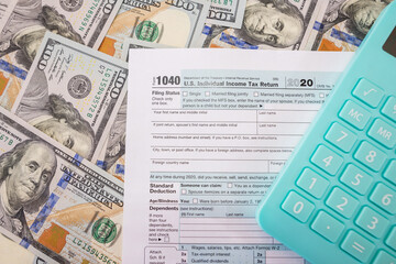 Tax form 1040 with a calculator on a money background.