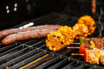 Grilling chicken kebab skewers and corn on a barbecue