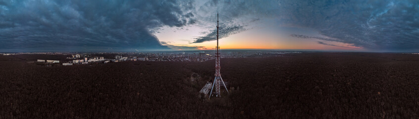 Aerial panorama after sunset, evening view on dark telecommunication tower antenna silhouette in...