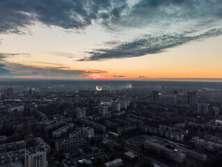 Aerial sunset evening view on residential Kharkiv city Pavlove Pole district. Gray multistory buildings with scenic bright orange cloudy sky on horizon