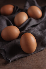 Brown chicken eggs close up on a gray napkin and dark background