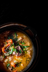 Pichelsteiner meat soup with vegetables in bowl on wooden table background