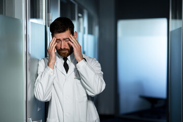 Tired doctor overworked at work, has a severe headache, feels bad, a man in the corridor of the clinic is disappointed with the result