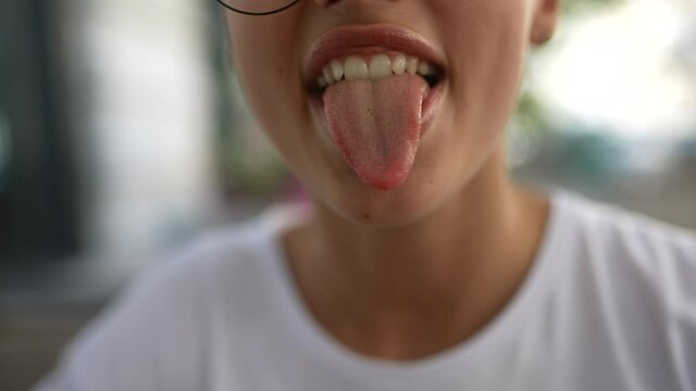 Girl's mouth close-up, moves lips and shows tongue