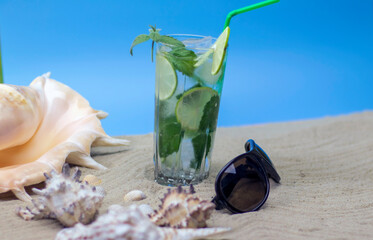 Summer cocktail on the sand of the beach, seashells and glasses. Rest on the seashore.