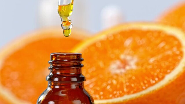 Super Slow Motion Shot of Oily Orange Essence Drop from Dropper into Phial at 1000fps.