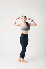 Full height photo of sport young woman, in sport wear, posing and showing her biceps