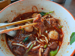 Top View of Thai boat noodles is Thailand's most famous noodles soup,Thai Boat noodles soup or Guay tiew reua ,Rice noodles thicken soup with stewed beef and beef ball. selective focus the beef