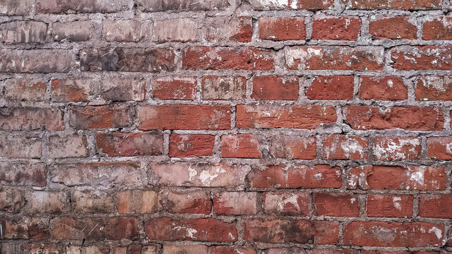 A horizontal section of an old dirty brick wall painted black and red.