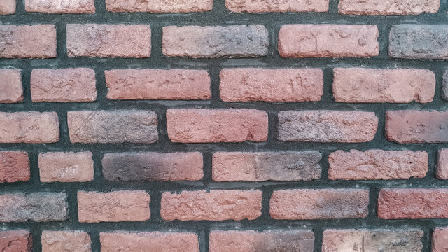 A horizontal section of an old brick wall painted black and red