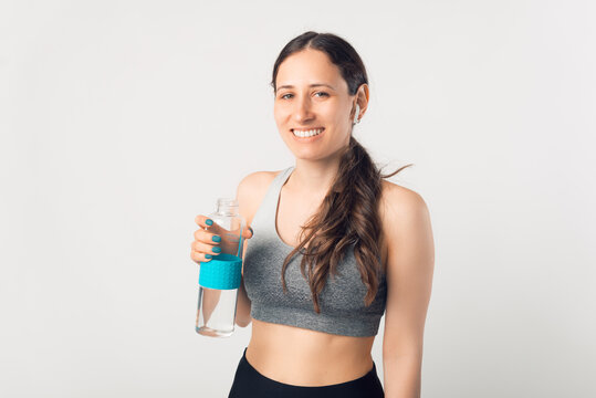 Image of a beautiful cheerful young sports woman posing isolated indoors drinking water