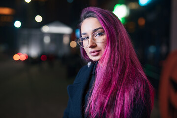 Portrait of unconventional woman with pink hair in the night city
